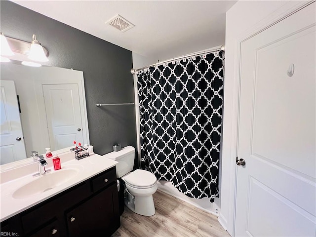 full bathroom featuring wood finished floors, a textured wall, curtained shower, vanity, and toilet