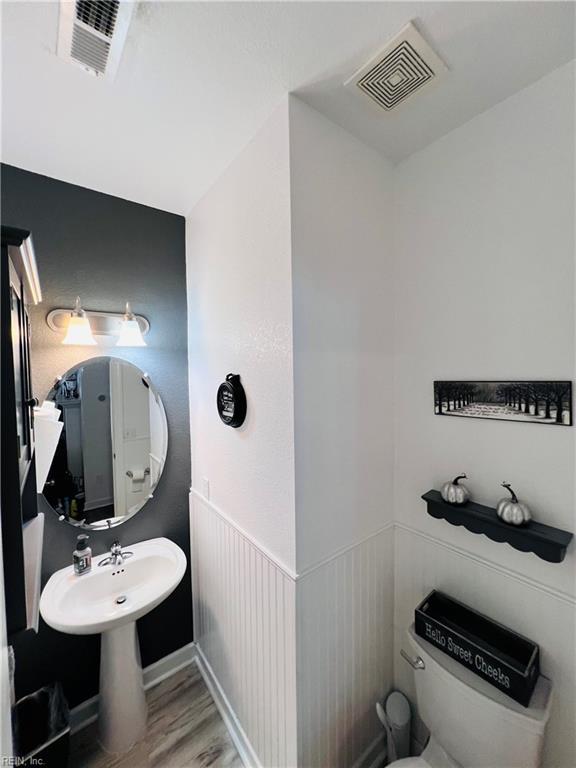 half bathroom with wood finished floors, toilet, and a sink