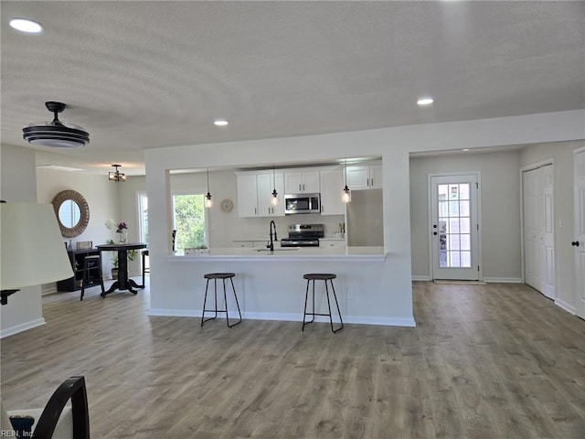 kitchen featuring stainless steel appliances, a sink, a breakfast bar area, recessed lighting, and baseboards