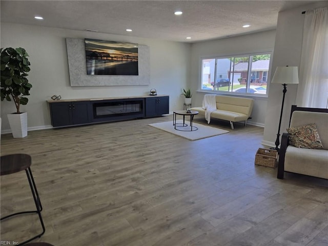 living room featuring recessed lighting, a textured ceiling, wood finished floors, and baseboards