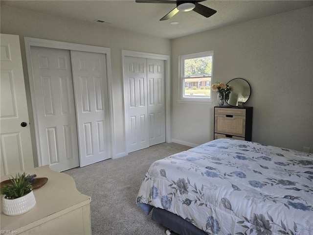 bedroom featuring two closets, carpet, and a ceiling fan