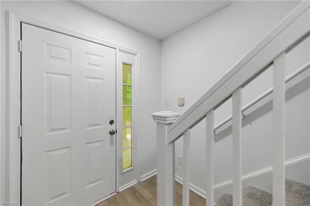 entrance foyer featuring light wood-style floors, a textured ceiling, and baseboards