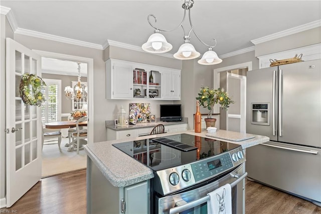 kitchen featuring appliances with stainless steel finishes, a chandelier, dark wood-type flooring, white cabinetry, and a kitchen island