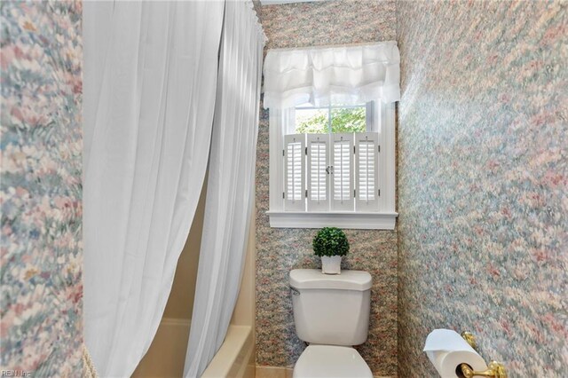 bathroom featuring toilet and shower / bath combination with curtain