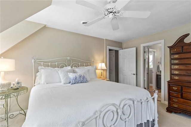 bedroom featuring light colored carpet, a ceiling fan, connected bathroom, and baseboards