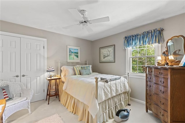 bedroom with light carpet, a closet, ceiling fan, and baseboards