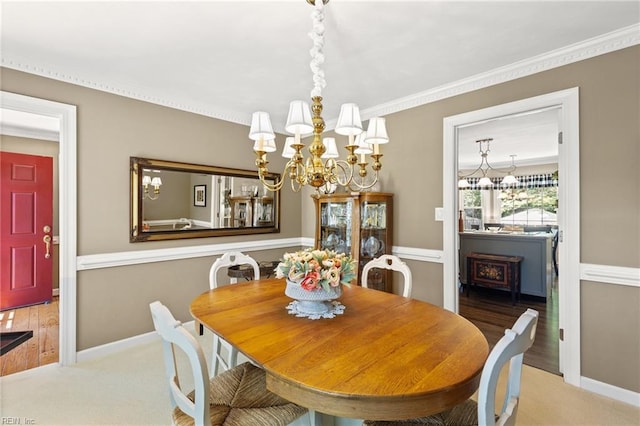 dining area featuring a chandelier, carpet flooring, baseboards, and crown molding