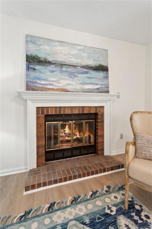 detailed view of a brick fireplace, baseboards, and wood finished floors