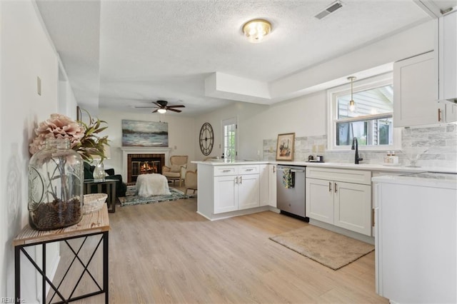 kitchen with dishwasher, a sink, a ceiling fan, light wood-style floors, and a peninsula