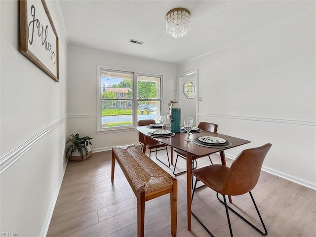 dining room featuring baseboards, light wood finished floors, and a chandelier
