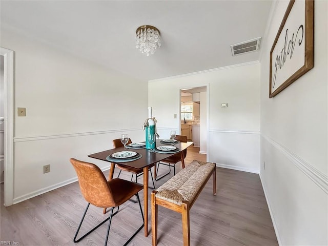 dining area with wood finished floors, baseboards, crown molding, and a chandelier