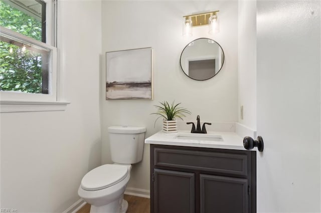 bathroom featuring toilet, vanity, baseboards, and wood finished floors