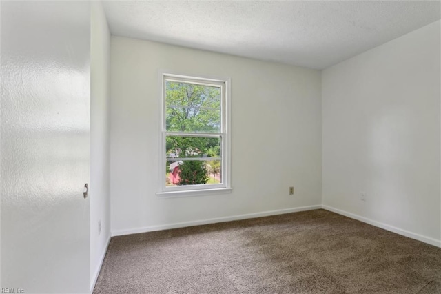 empty room featuring carpet flooring, baseboards, and a textured ceiling