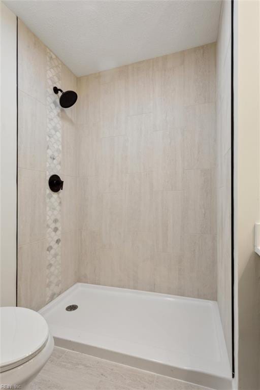 bathroom featuring a tile shower and toilet