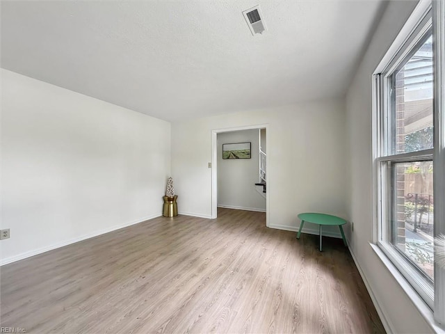 unfurnished room featuring light wood-type flooring, baseboards, and a textured ceiling