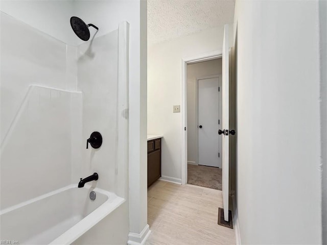 bathroom with shower / tub combination, vanity, a textured ceiling, baseboards, and wood finished floors