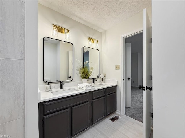 full bath featuring double vanity and a textured ceiling
