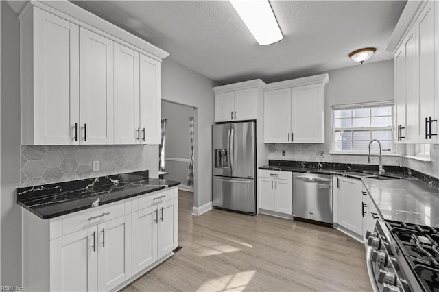 6738 Burbage Landing Cir, Suffolk, VA 23435 - kitchen featuring appliances with stainless steel finishes, white cabinets, a sink, backsplash, and light wood-type flooring