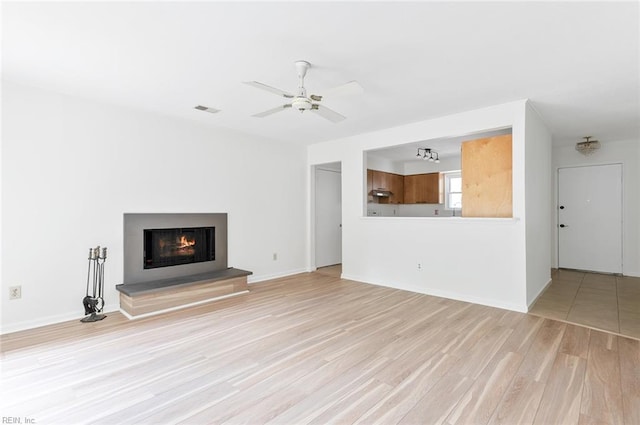13024 Green Grove Ln, Newport News, VA 23608 - unfurnished living room with light wood finished floors, a warm lit fireplace, a ceiling fan, and baseboards
