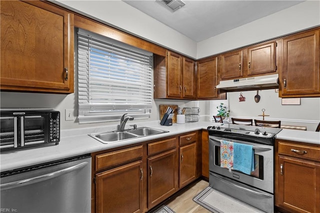 3412 Winterhawk Ct, Chesapeake, VA 23323 - kitchen featuring under cabinet range hood, a sink, appliances with stainless steel finishes, light countertops, and brown cabinetry