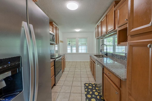 100 Woodland Cir, Franklin, VA 23851 - kitchen featuring appliances with stainless steel finishes, a sink, brown cabinetry, a textured ceiling, and light tile patterned floors