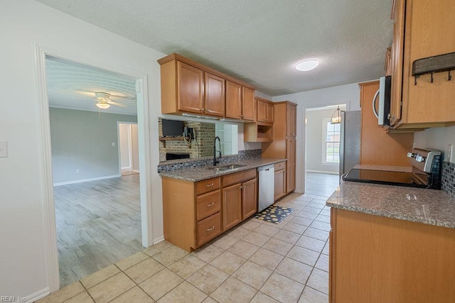 100 Woodland Cir, Franklin, VA 23851 - kitchen with appliances with stainless steel finishes, a sink, a textured ceiling, brown cabinetry, and light tile patterned floors
