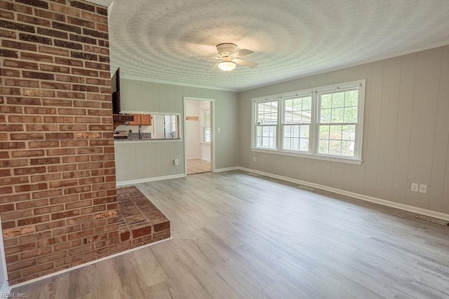 100 Woodland Cir, Franklin, VA 23851 - unfurnished living room featuring ceiling fan, light wood-type flooring, baseboards, and a textured ceiling