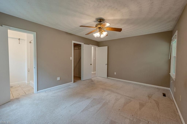 100 Woodland Cir, Franklin, VA 23851 - unfurnished bedroom with carpet, a walk in closet, baseboards, connected bathroom, and a ceiling fan