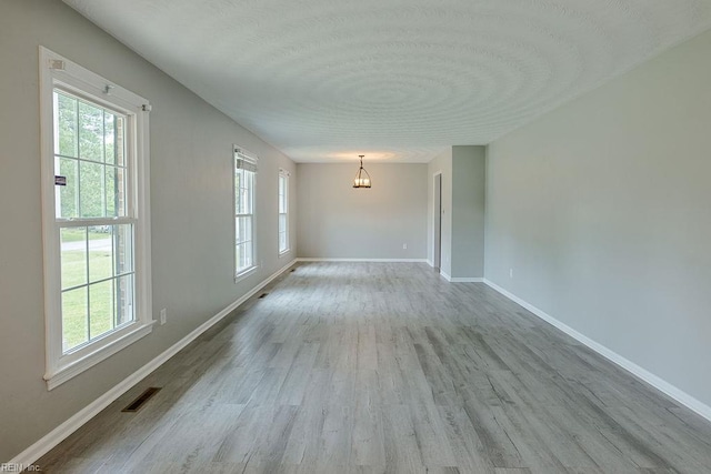 100 Woodland Cir, Franklin, VA 23851 - empty room featuring a chandelier, wood finished floors, baseboards, and a textured ceiling