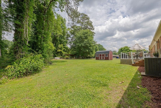 view of green lawn featuring central air condition unit, a storage shed, and an outdoor structure