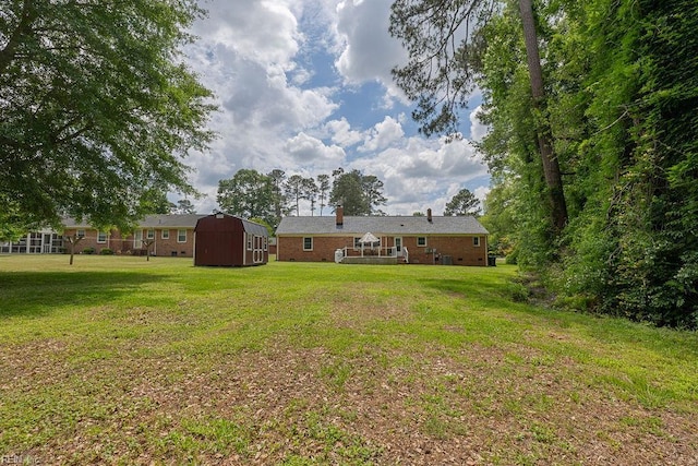 view of grassy yard with a storage shed and an outbuilding