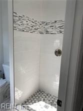 full bath with toilet and tiled shower