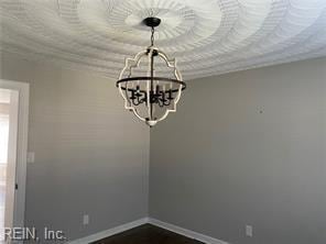 unfurnished dining area featuring a chandelier and baseboards