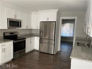 kitchen with stainless steel appliances, a sink, dark wood-style floors, white cabinets, and light stone countertops