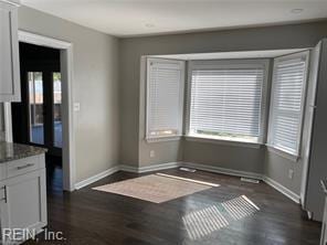 unfurnished dining area with dark wood-style flooring, healthy amount of natural light, and baseboards