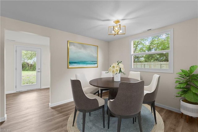 dining area with a chandelier, wood finished floors, and baseboards