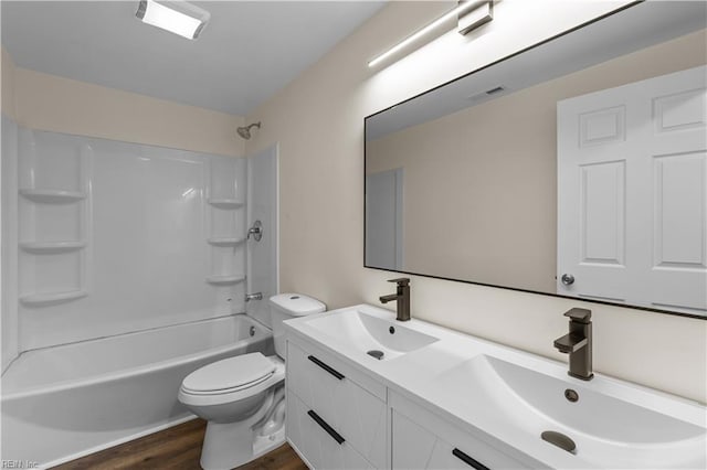 bathroom with wood finished floors, toilet, tub / shower combination, and double vanity