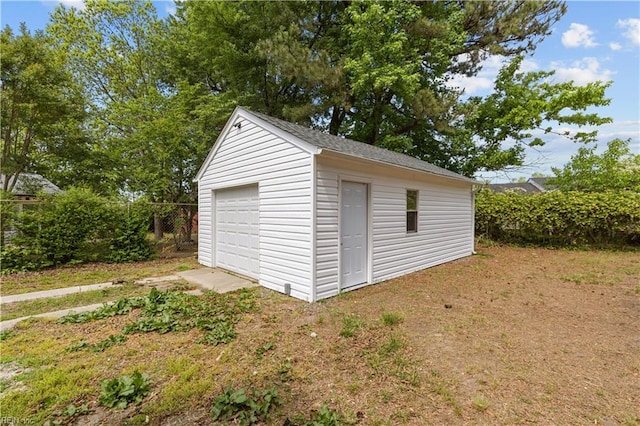 view of outdoor structure with an outdoor structure, driveway, and fence