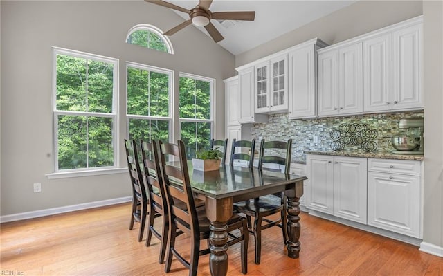 dining area featuring a ceiling fan, lofted ceiling, light wood-style flooring, and baseboards