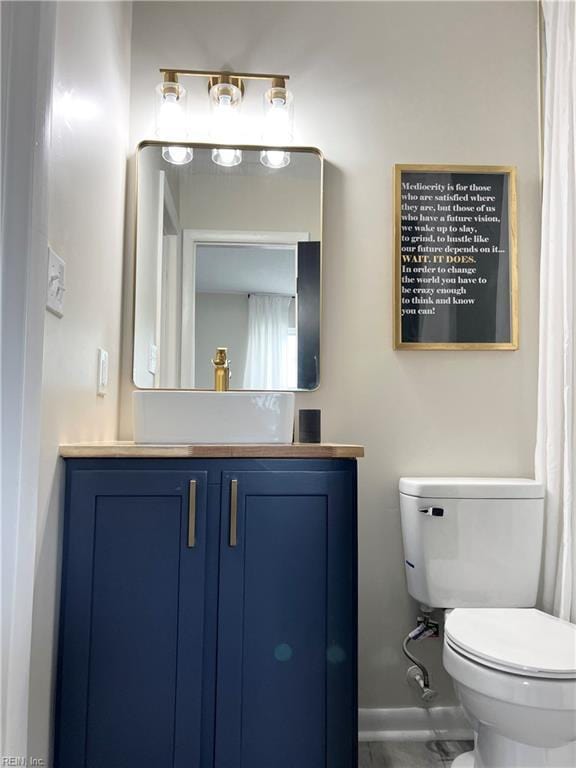 bathroom with baseboards, vanity, and toilet