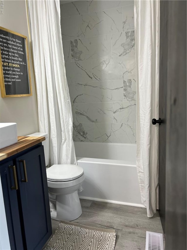 full bathroom with wood finished floors, shower / bathtub combination with curtain, toilet, and vanity