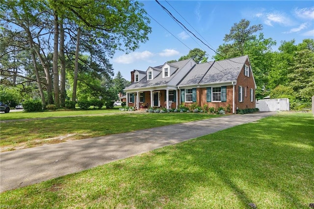 cape cod house featuring brick siding, a front lawn, concrete driveway, and a porch