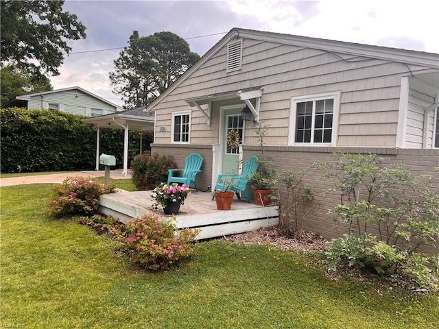 back of property featuring a yard, a deck, and brick siding