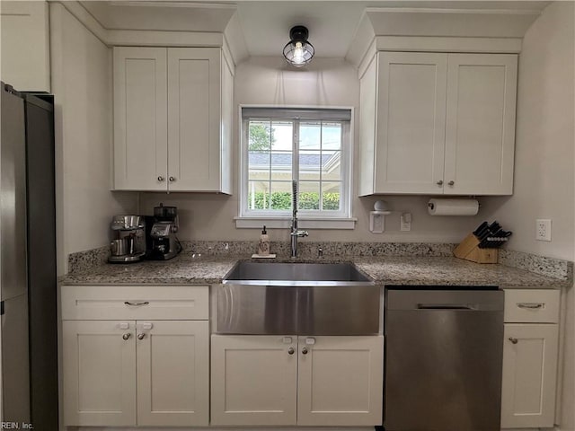 kitchen featuring stainless steel appliances, a sink, white cabinets, and light stone countertops