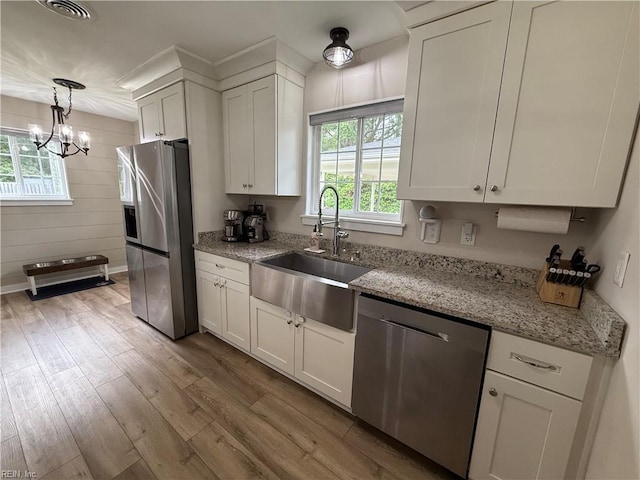 kitchen with appliances with stainless steel finishes, a sink, light wood-type flooring, and white cabinets
