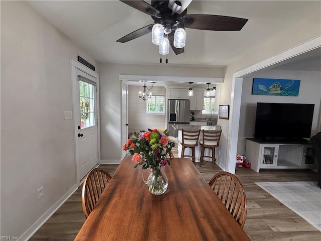 dining room with a ceiling fan, wood finished floors, a chandelier, and baseboards