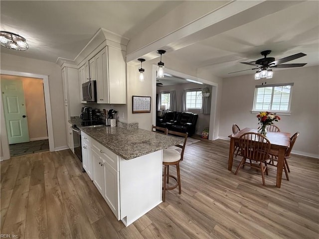 kitchen featuring stainless steel microwave, electric range oven, light wood-style floors, white cabinetry, and light stone counters