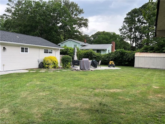 view of grassy yard featuring a storage shed, an outdoor structure, and a patio