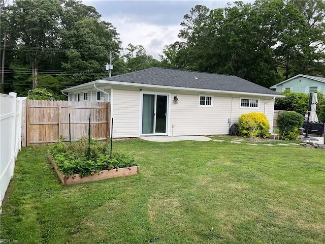 rear view of property featuring a vegetable garden and roof with shingles