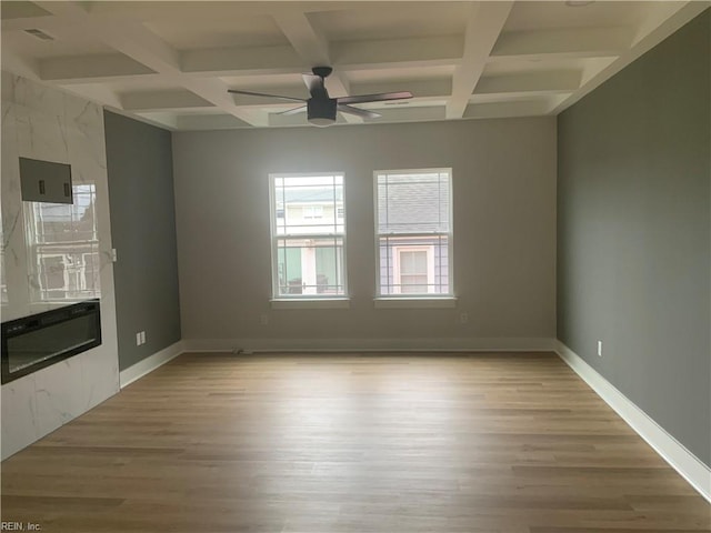 unfurnished living room featuring coffered ceiling, ceiling fan, light wood-type flooring, beamed ceiling, and baseboards